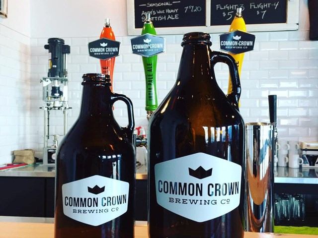 Two brown growlers with Common Crown logo in a brewery.