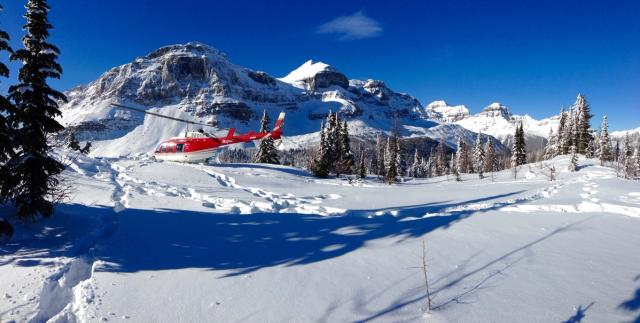 Helicopter landing in a snowy field in the mountains in Banff National Park