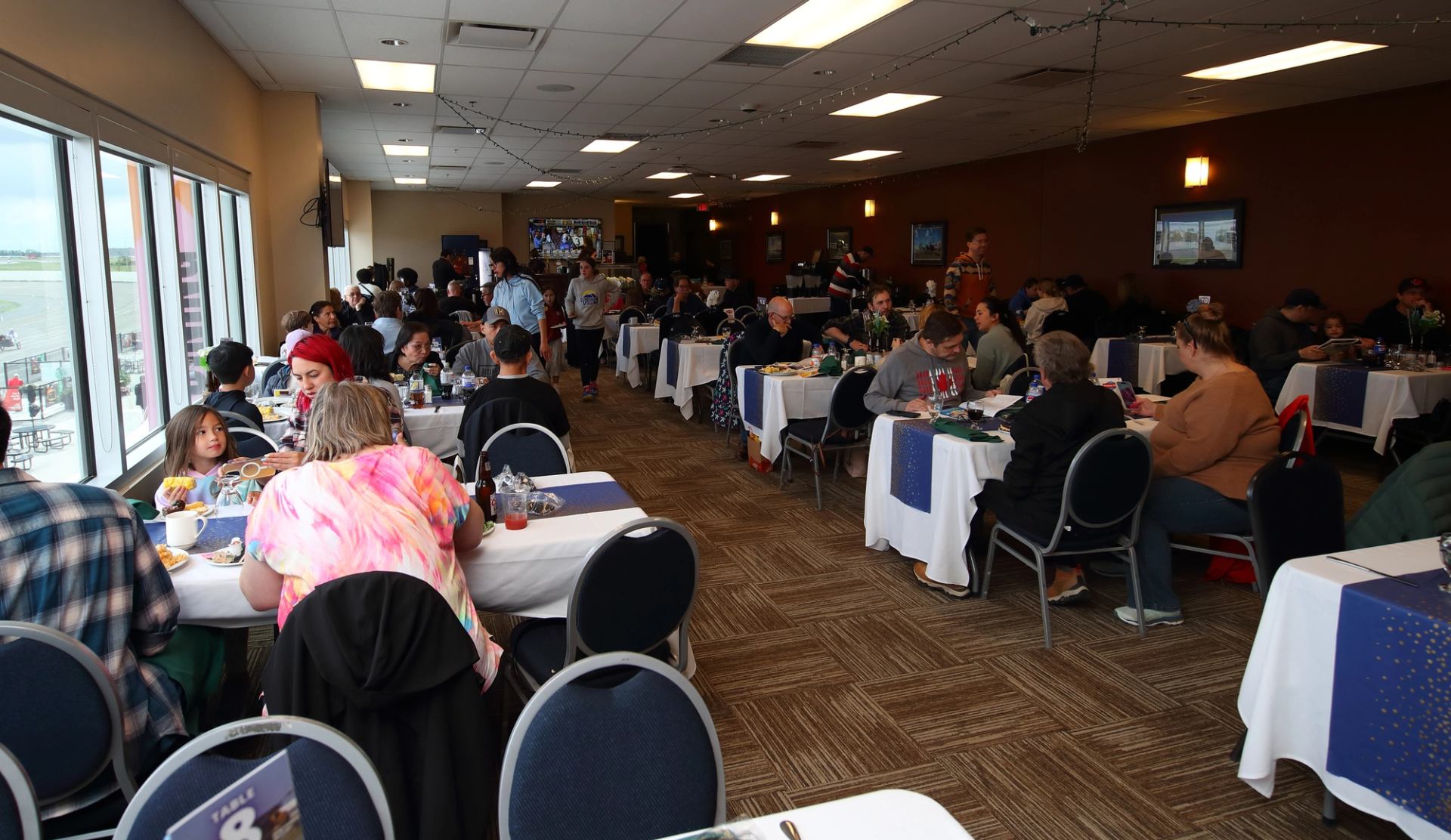 Guests enjoying a meal in a decorated dining area with large windows
