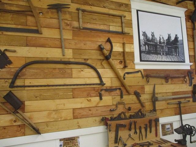 Museum wall displays vintage firearms, tools, and framed black-and-white photo.