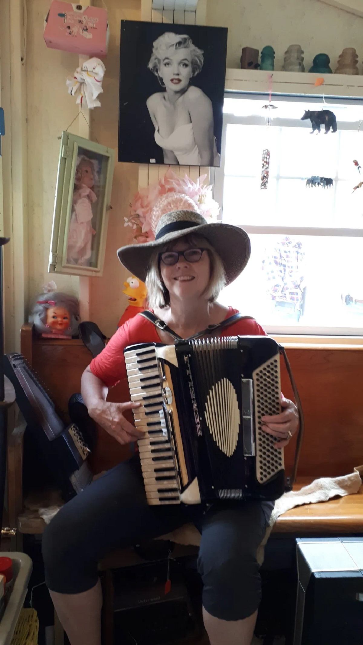 Person playing accordion indoors with vintage wall art, cozy decor, and warm natural light.