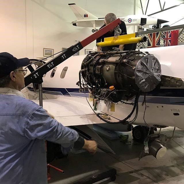 Technicians working on aircraft engine inside hangar.