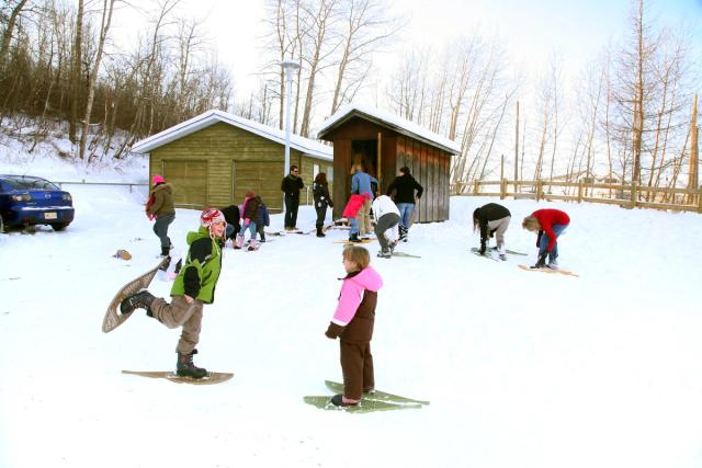 Families snowshoeing near a cabin at the Strathcona Wilderness Centre in Ardrossan.