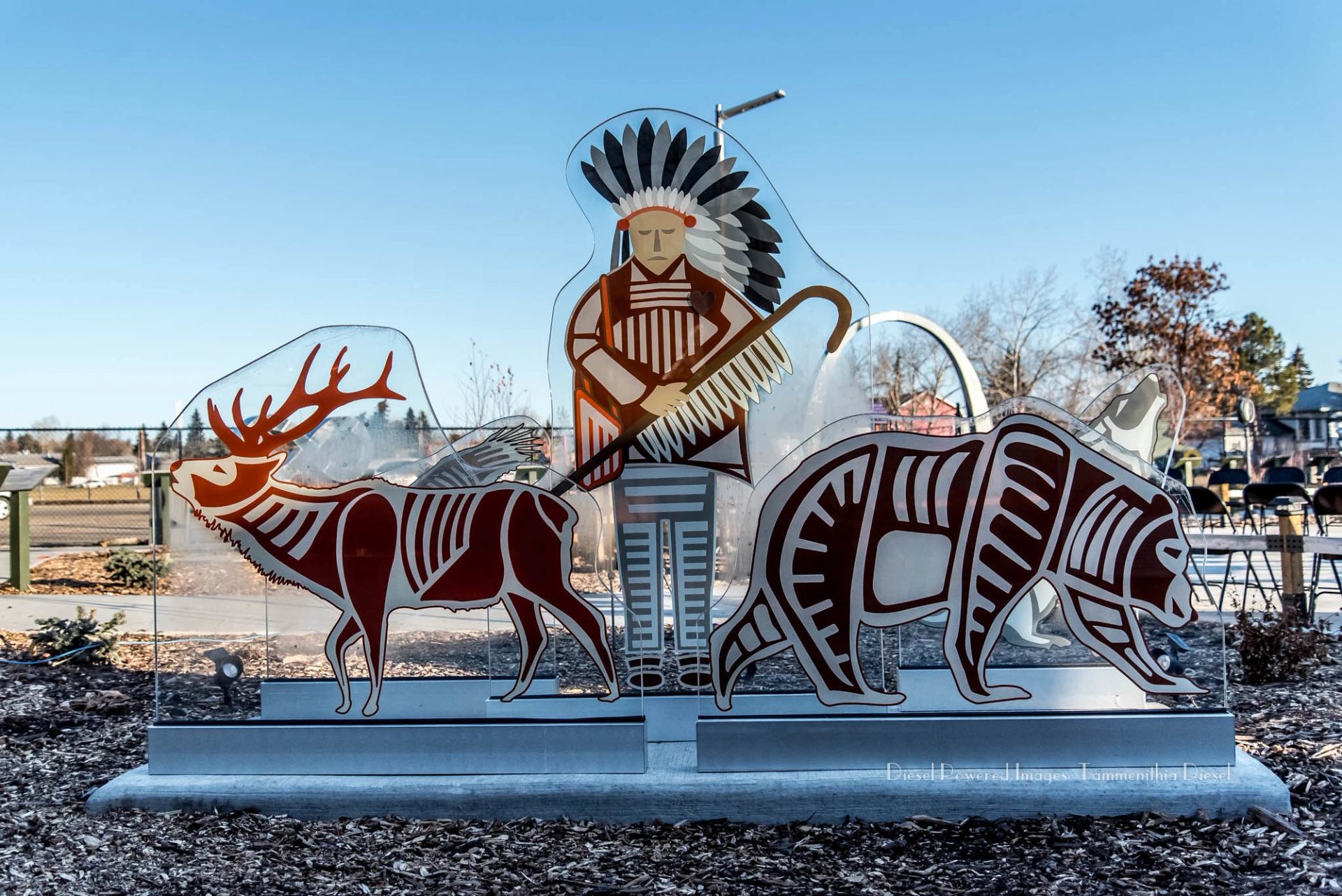 Outdoor sculpture featuring stylized figures of a person, deer, and bear