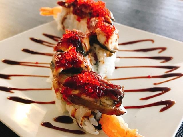 Sushi rolls with eel, dark sauce, and red roe on white plate from Kiri Japanese Cuisine.