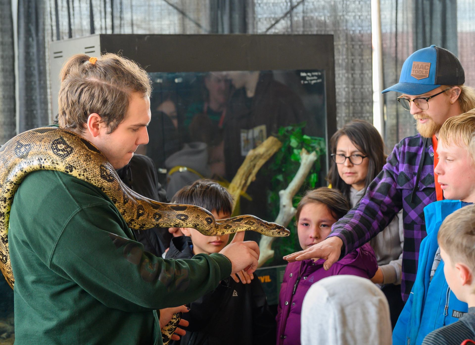  Group gathered around a handler holding a large snake for guests to observe.