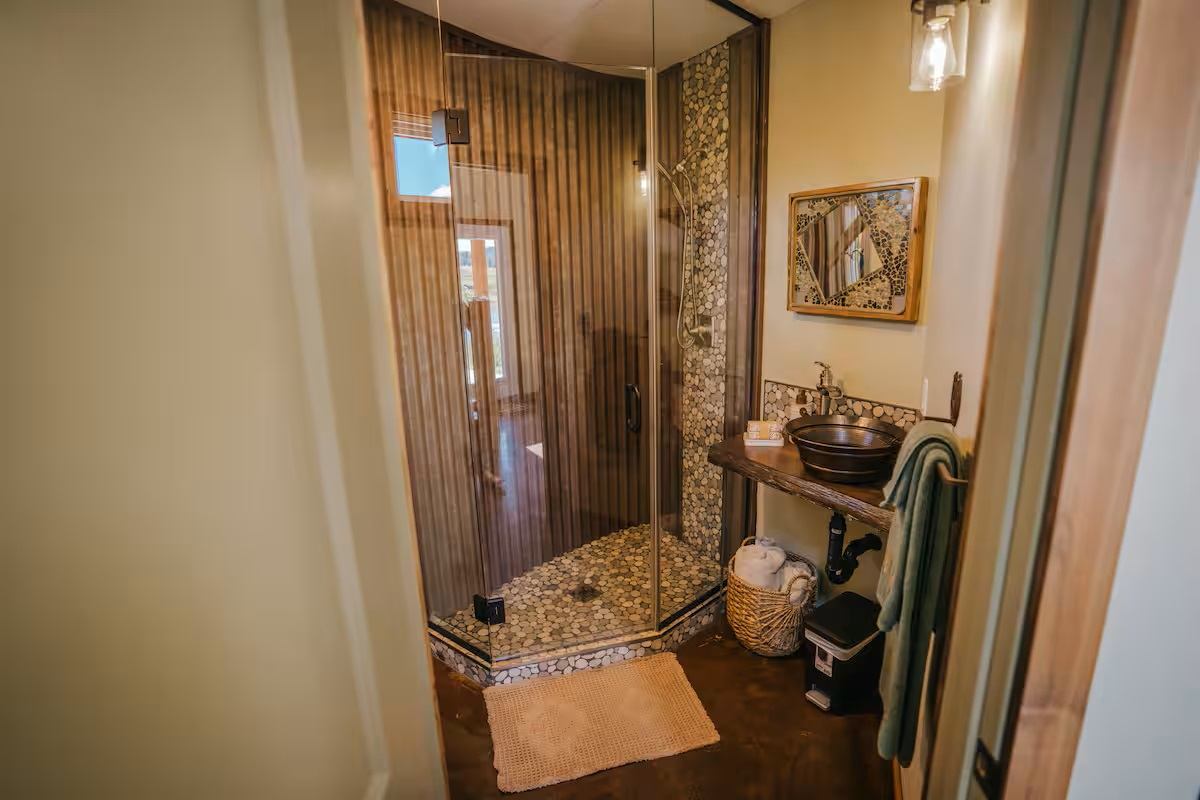 Saddle Hill Ranch bathroom with glass shower, stone accents, and rustic vanity.