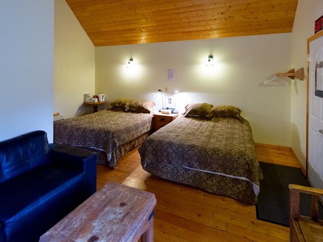 Cozy lodge room with double beds, wood decor, and rustic furnishings.