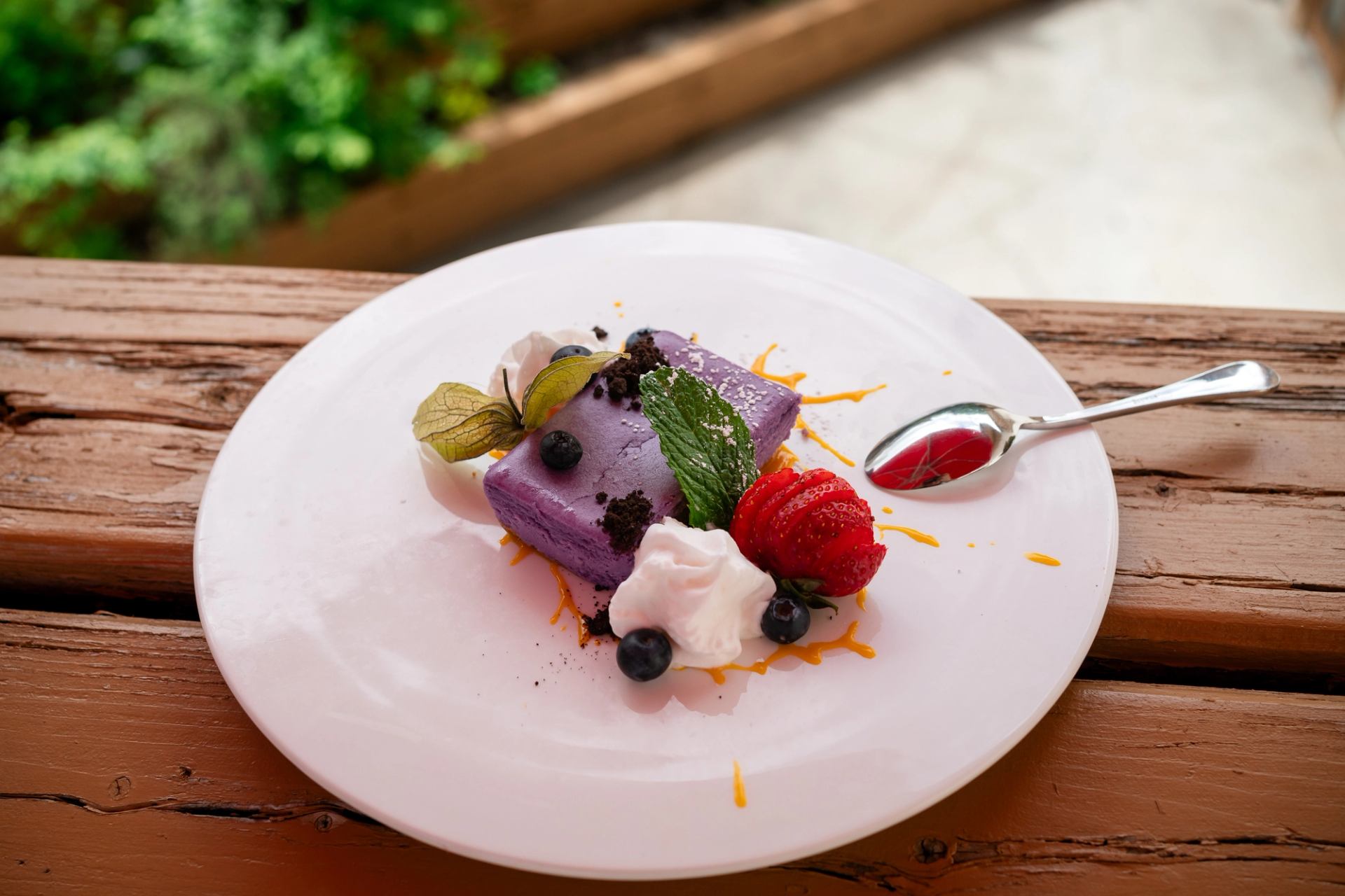 Purple ube cheesecake with fresh berries and mint garnish.