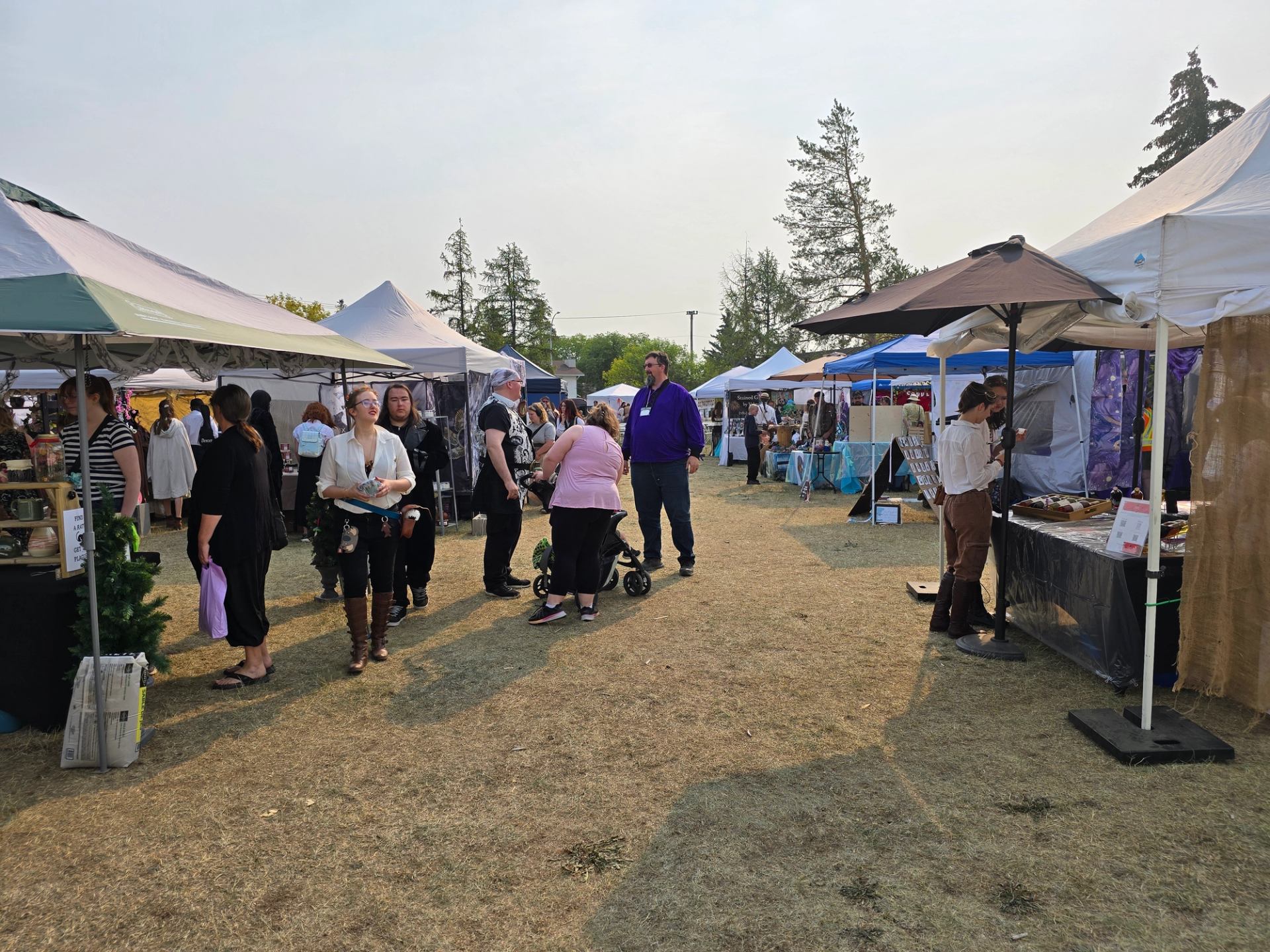 People walking through rows of vendor tents at an outdoor market.