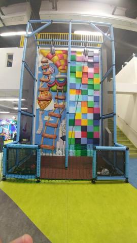 A multicolored climbing wall with a rope.