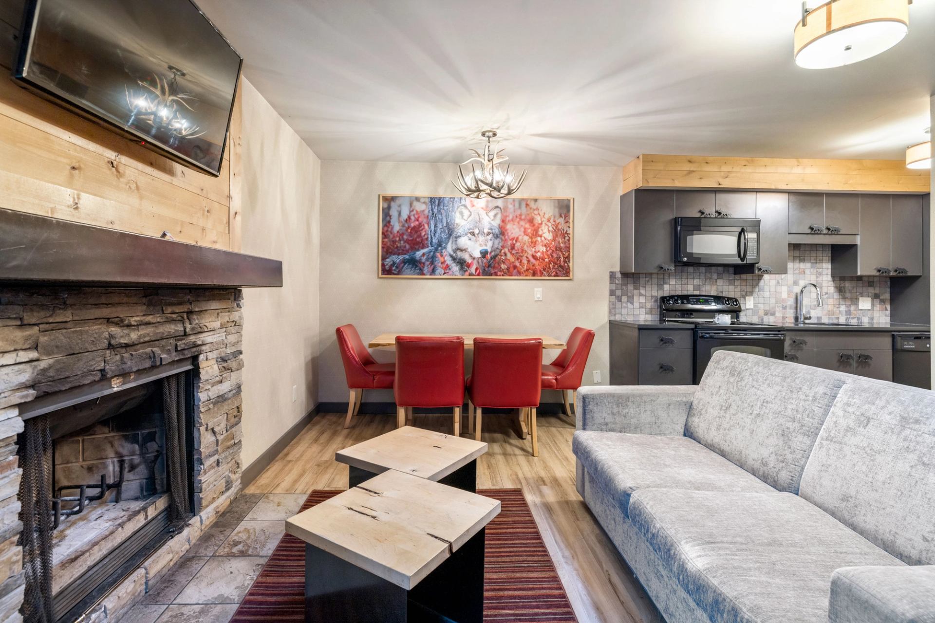 Living and dining area with red dining chairs, grey couch and a dark grey kitchen in the background.