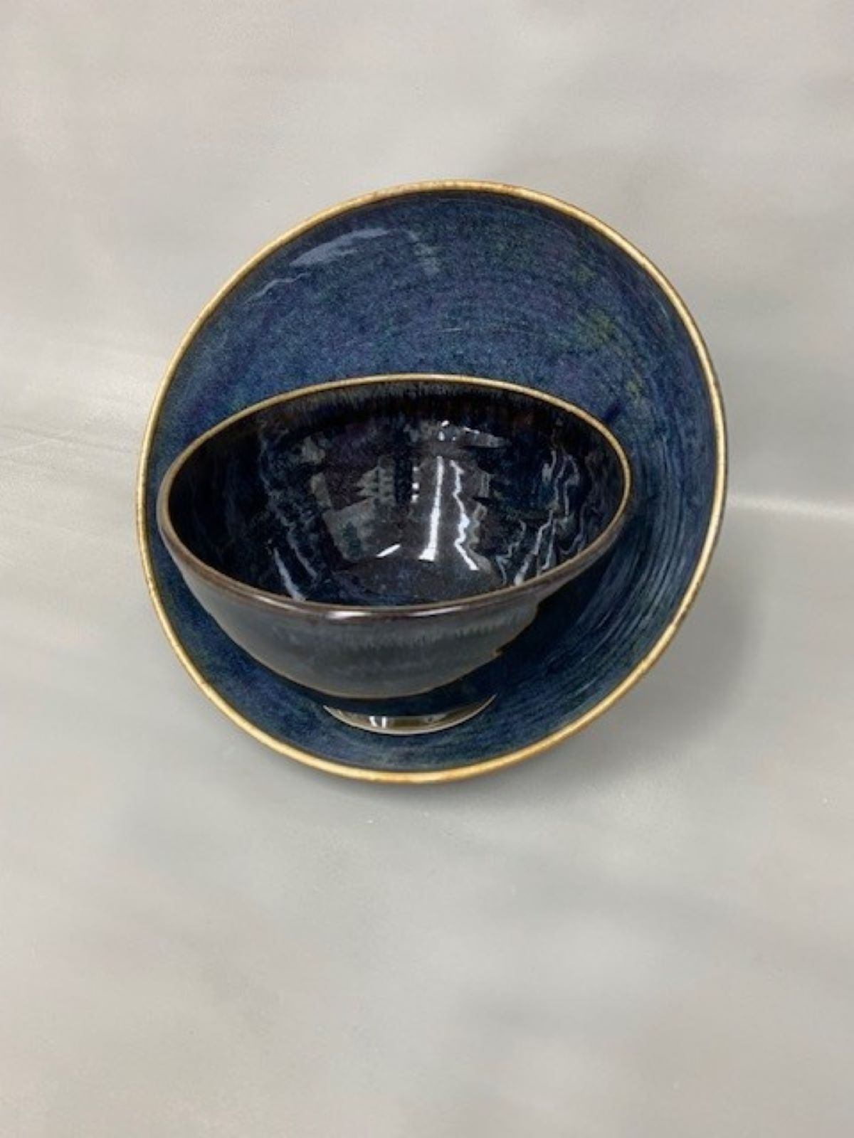 Blue-glazed handmade ceramic cup with a gold rim, photographed from above.
