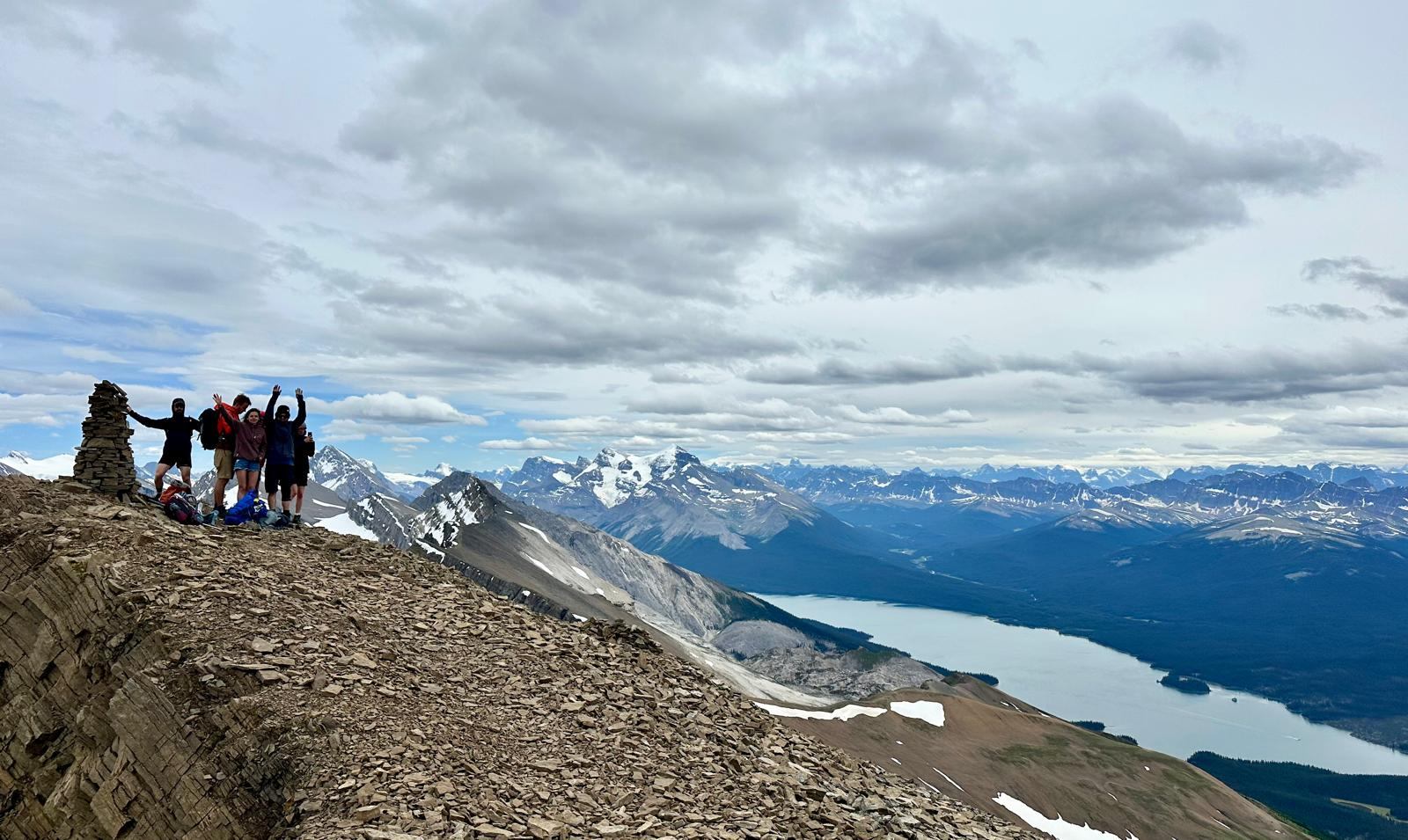 Hiking group standing on top of mountain, high above a glacier lake.