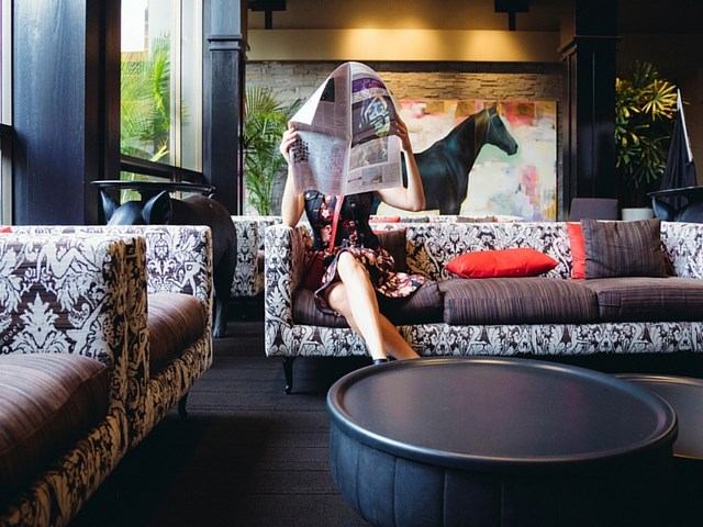 Hotel lounge with patterned sofas, red cushions, and horse artwork in natural light.