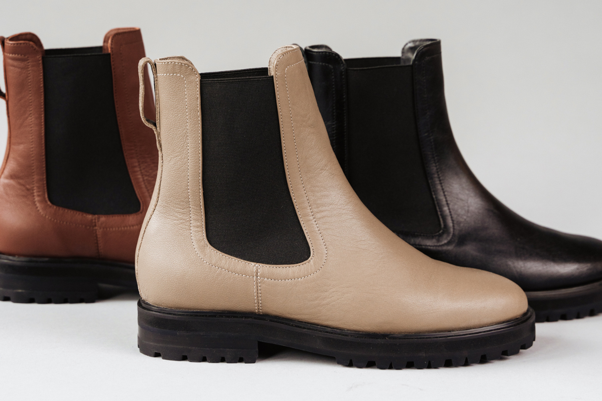 Trio of Chelsea boots in beige, black, and brown with rugged soles and elastic panels.