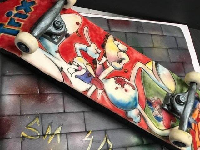Colorful skateboard‑style cake decorated with vibrant cartoon artwork.