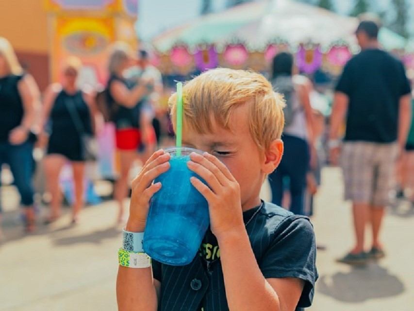 A boy enoying a drink at the fair