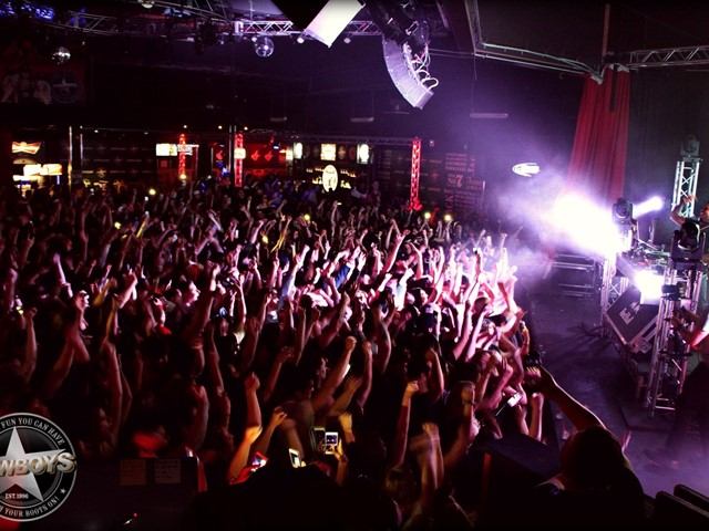 Crowd dancing under bright lights at Cowboys Dance Hall.