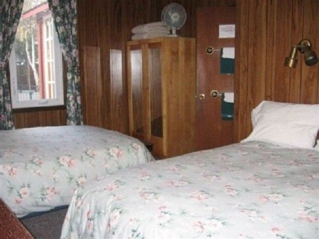 Double beds with floral decor in a cozy, wood-paneled room at Tan-Y-Bryn B&B Inn.