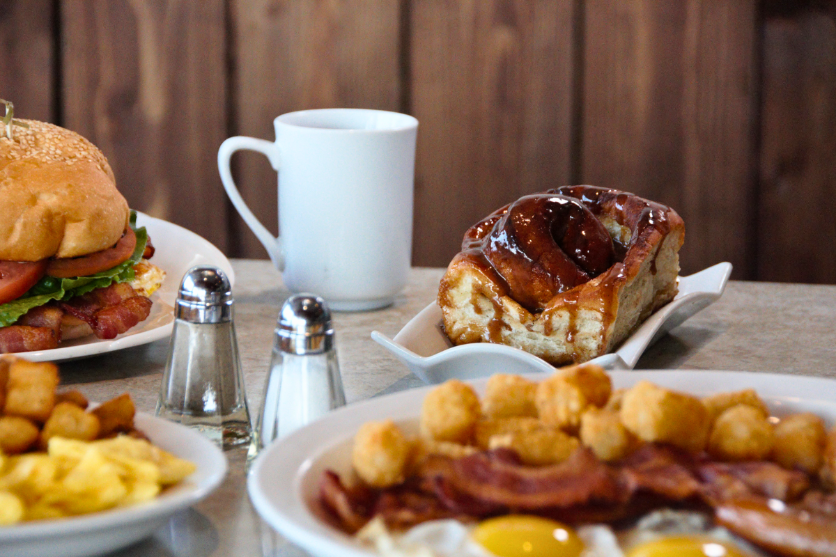 Breakfast spread with eggs, bacon, tater tots, sandwich, pastry, and coffee at Grande Cache Inn.