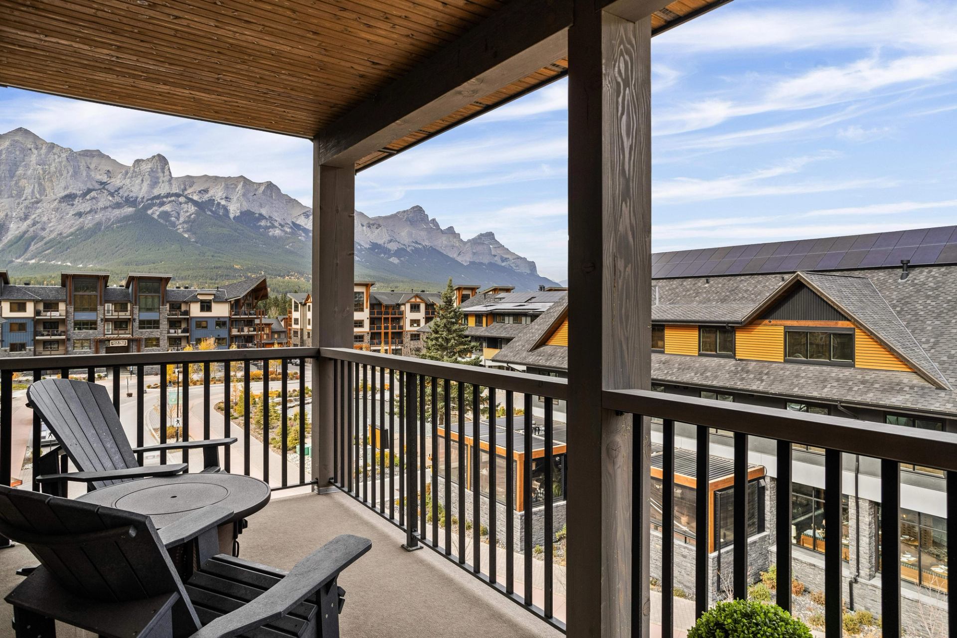 Covered balcony with chairs overlooks lodge buildings and rugged mountains.