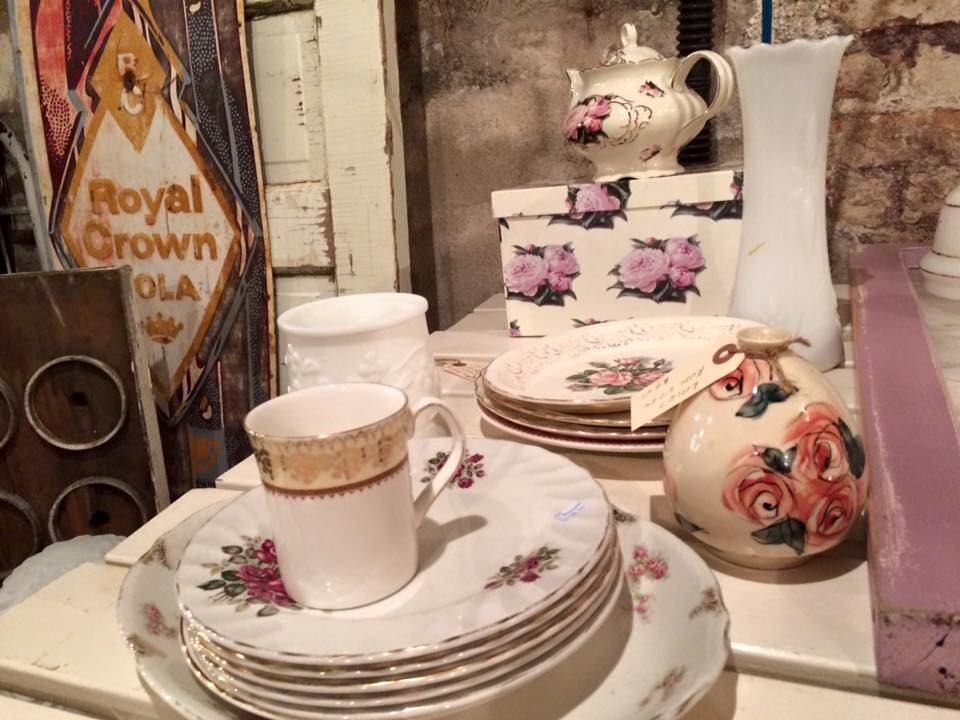 Antique teapot and cups on a table with floral china and stacked plates.