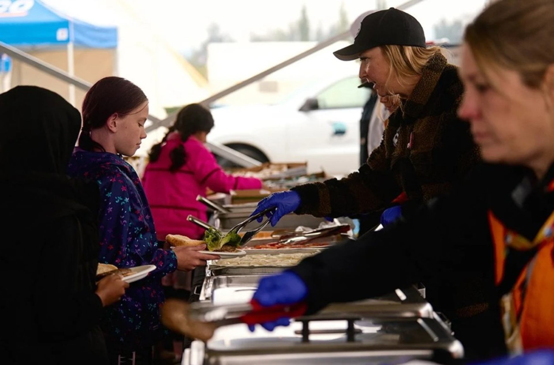 Volunteer serves food to children at cultural festival