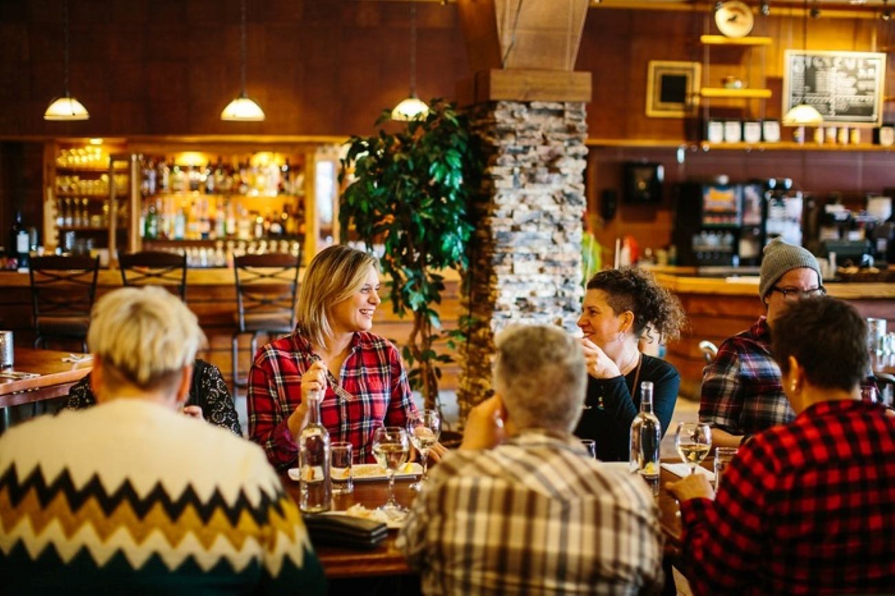 Group gathered around a table inside a cozy restaurant, enjoying food and drinks together.