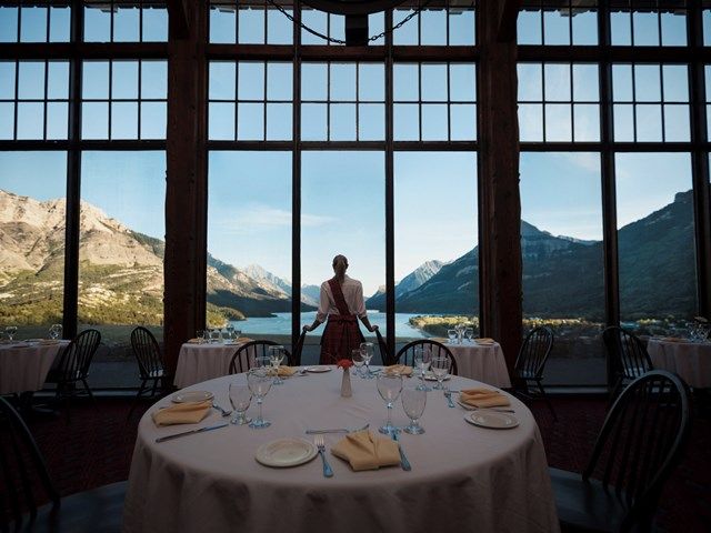 Waitress looking out restaurant windows to the lake at the Price of Wales Hotel in Waterton.