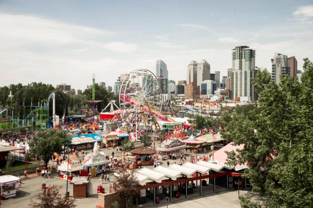 Wide shot of Stampede Park showing midway, Ferris wheel and city skyline.