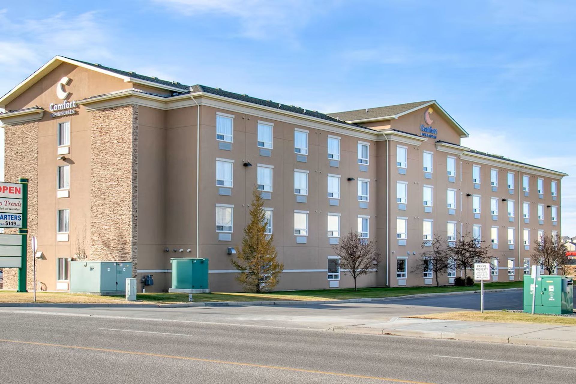 Exterior view of Comfort Inn & Suites hotel building with multi-story facade and clear sky.