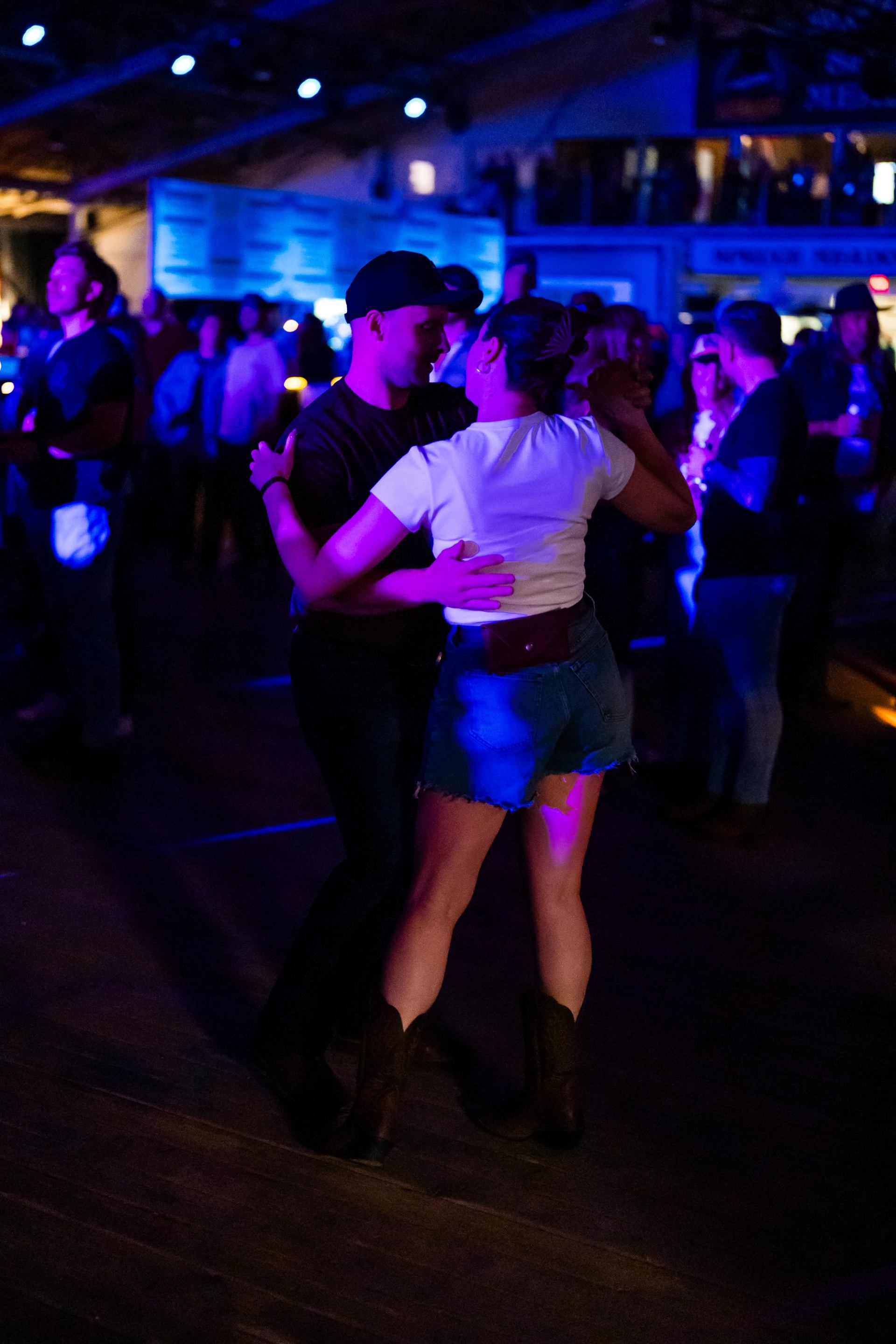 Two people dancing in a lively, colorful concert crowd.
