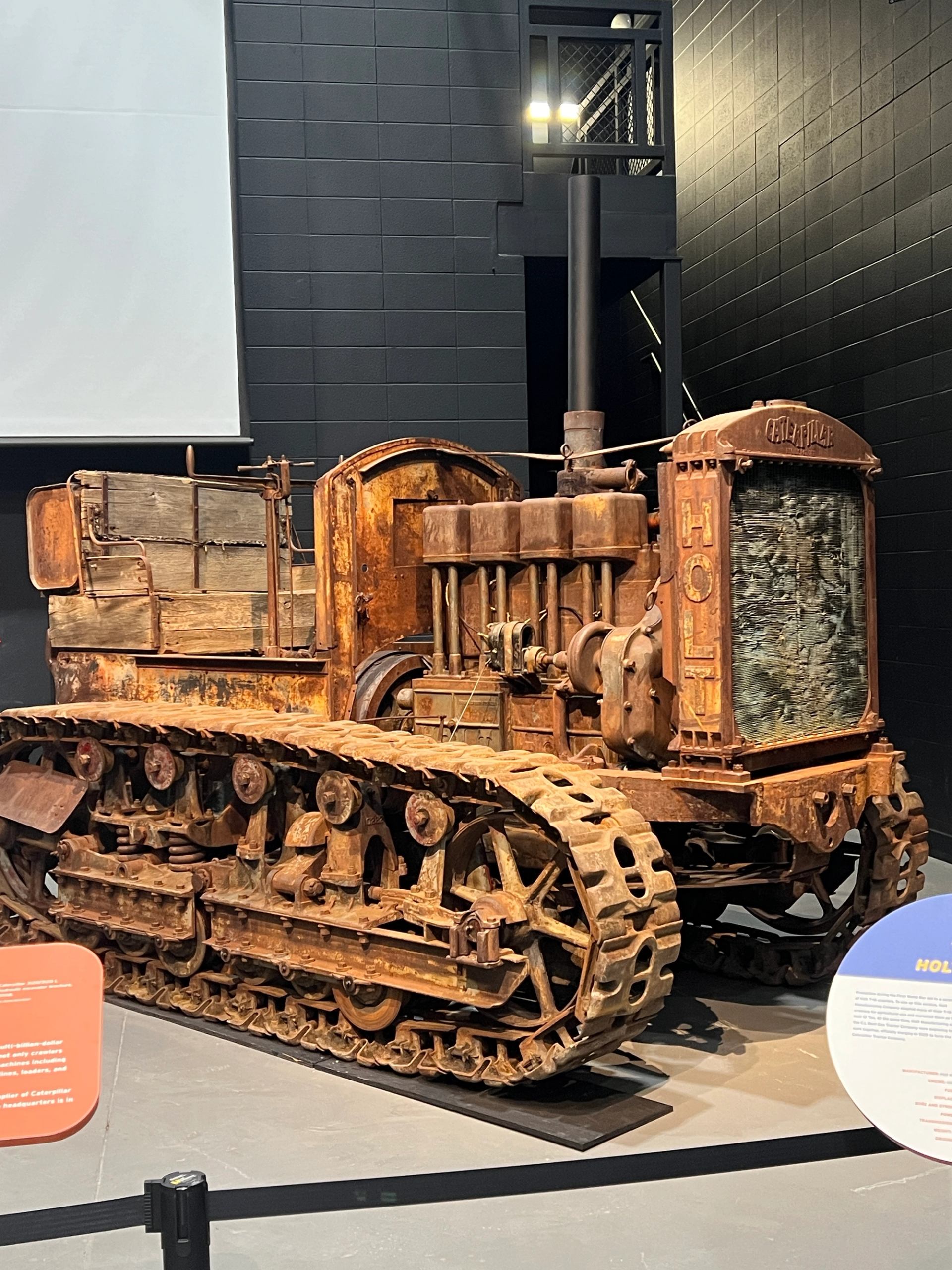 Restored tracked snow machine display with large metal grille and headlights in museum.