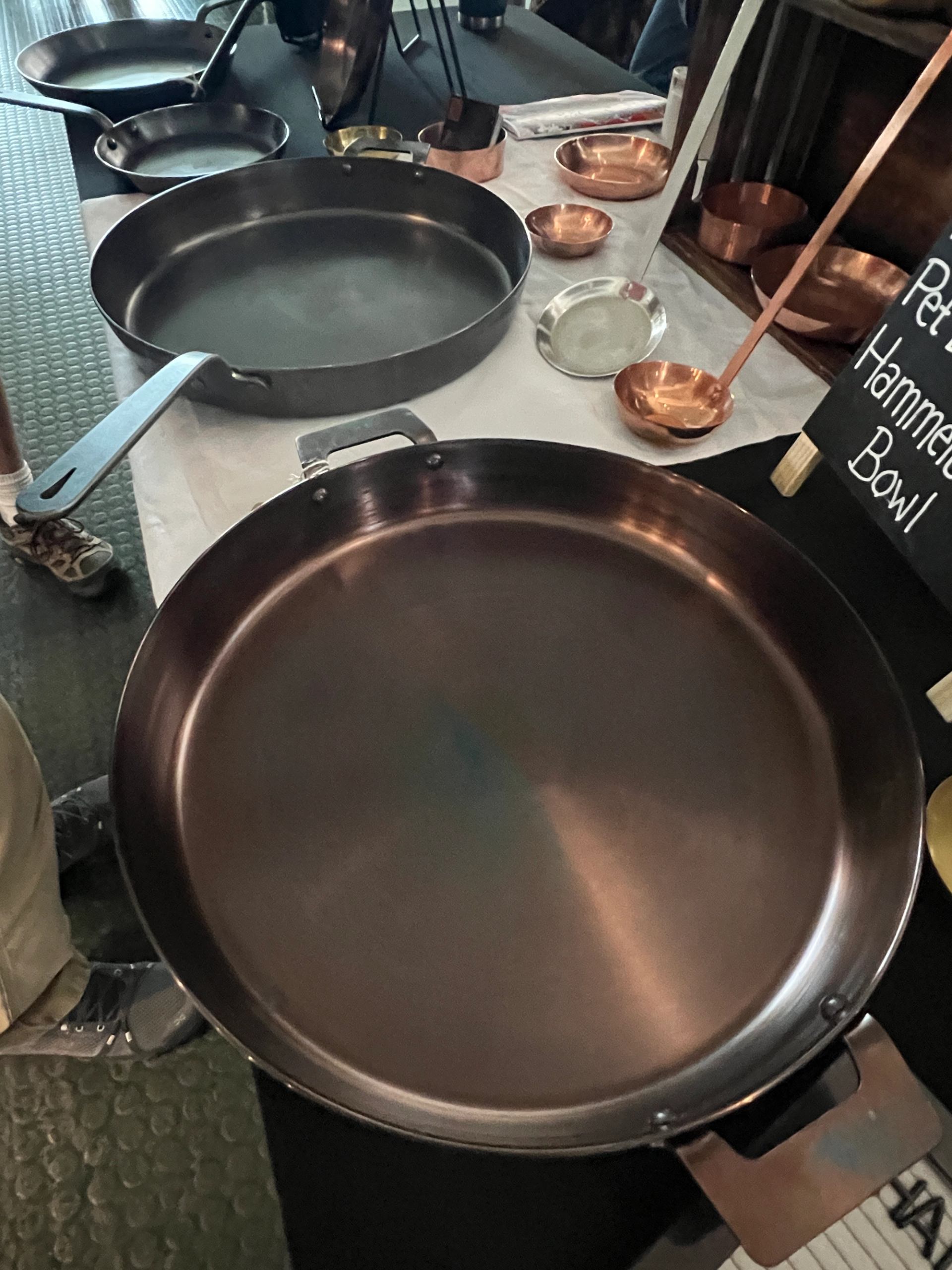 Large handcrafted metal pans and bowls displayed on a table.