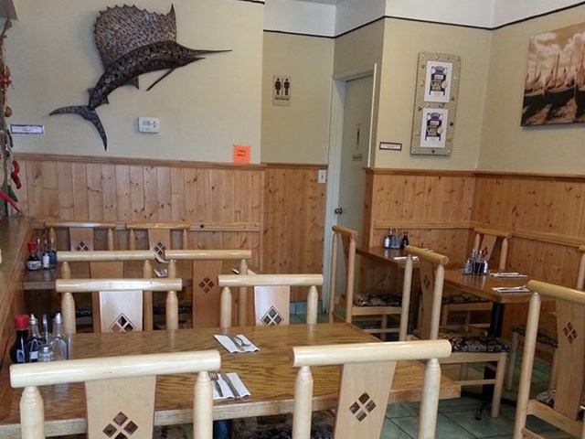 Wood-paneled dining space with tables and wall art inside The New Mr. Spud Café
