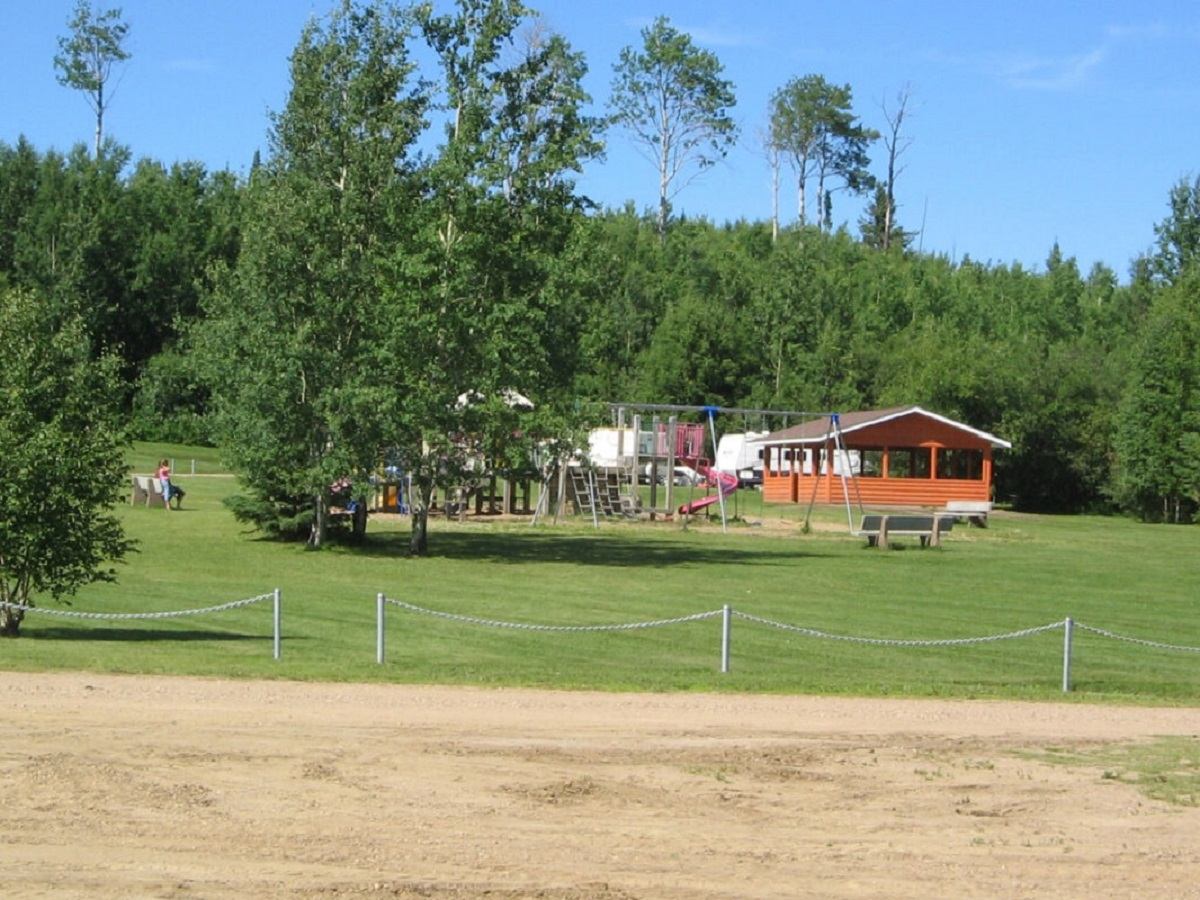 Playground and picnic shelter surrounded by green trees at Wadlin Lake Park.