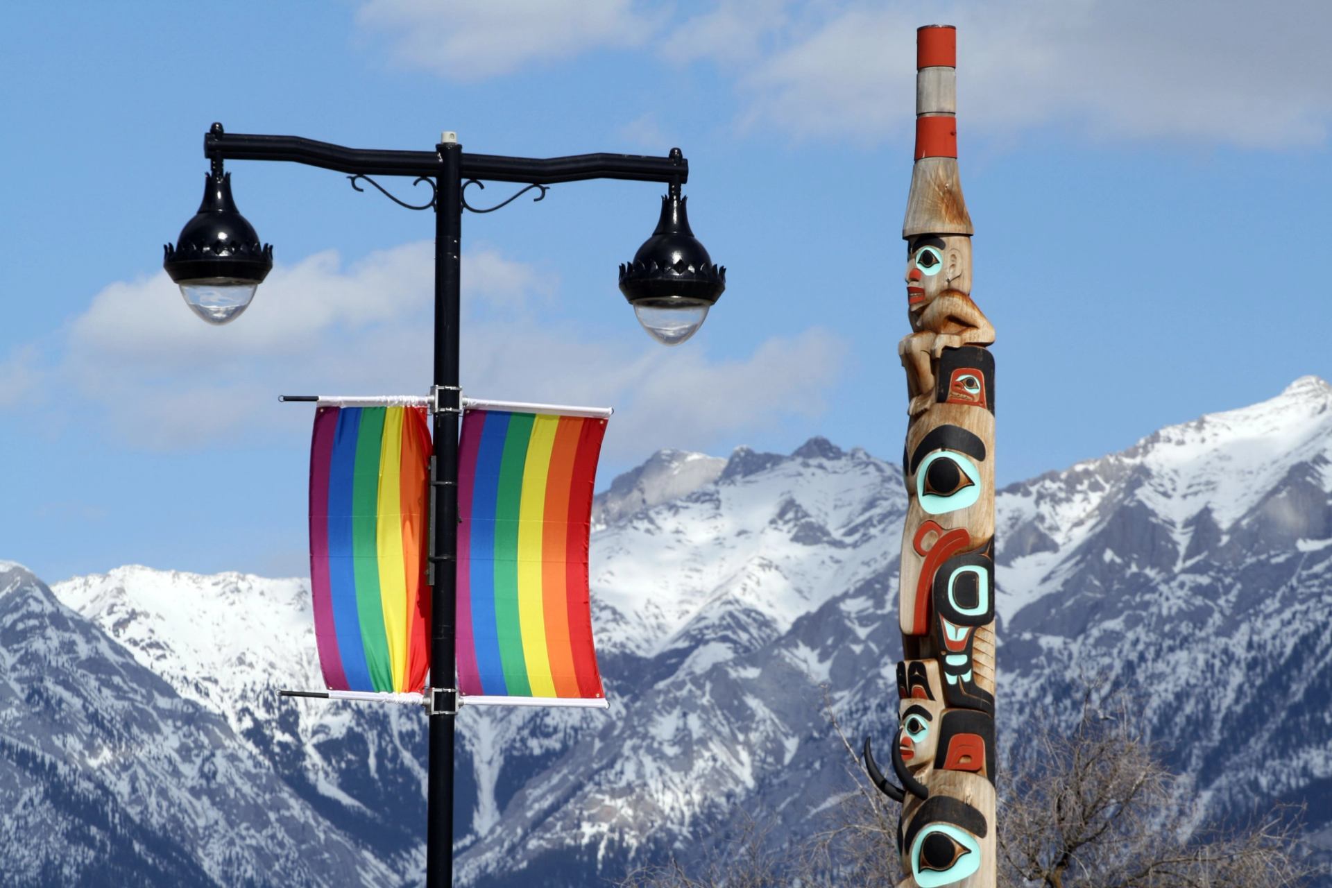 A rainbow banner and a decorated pole with snowy mountains in the background.