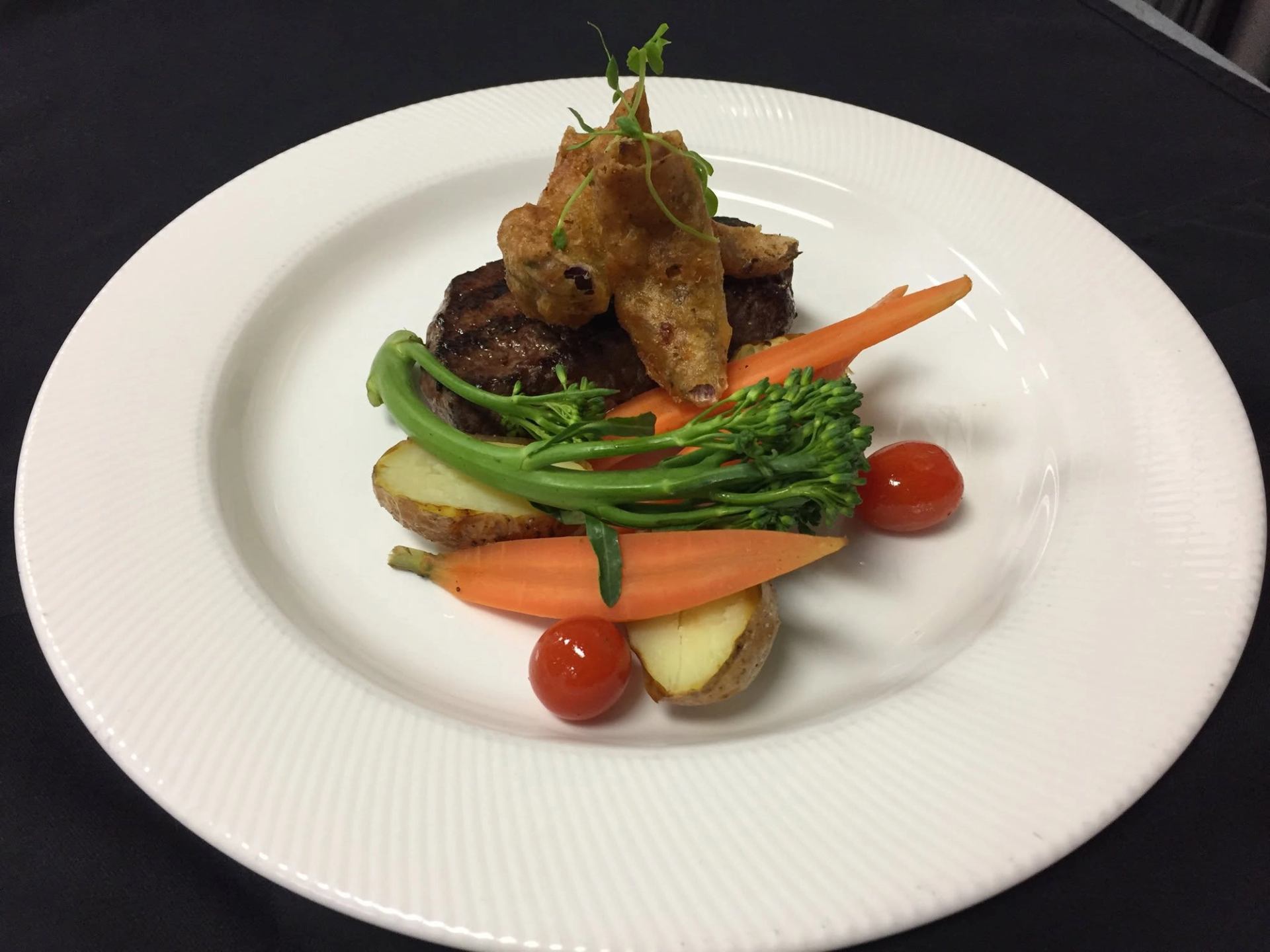 West 67 Lounge & Grill presents a steak entrée with vegetables, potatoes, and crispy garnish.