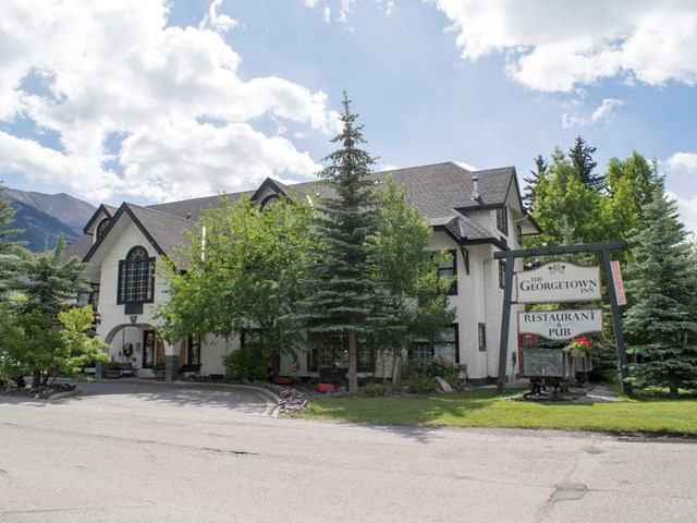 Charming alpine-style inn with trees and mountains in the background.