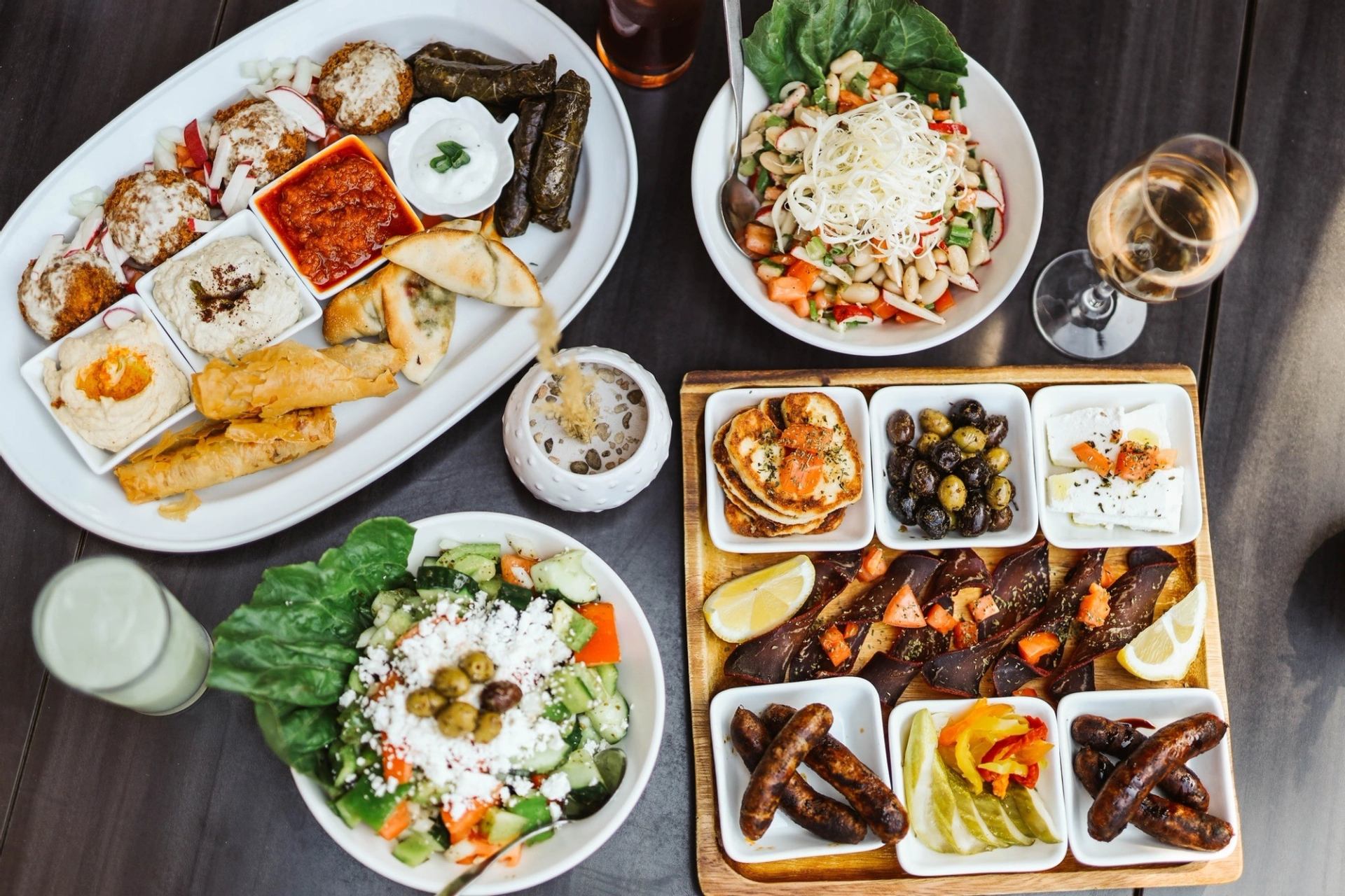 Assorted Mediterranean dishes with salads, dips, grilled meats, and wine at Aida’s Bistro.