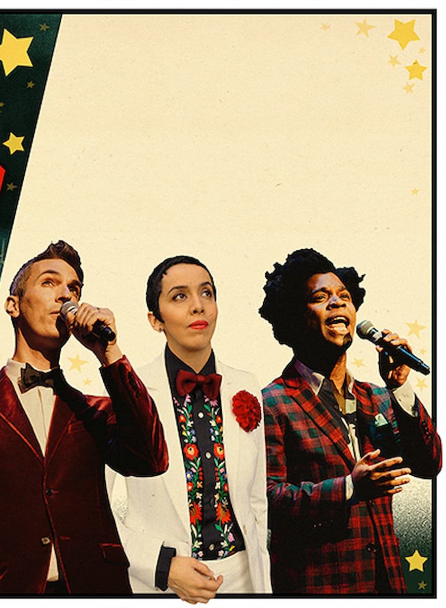 Three performers, two men and a woman, in festive suits and bow ties, look up against a starry background; two hold microphones.