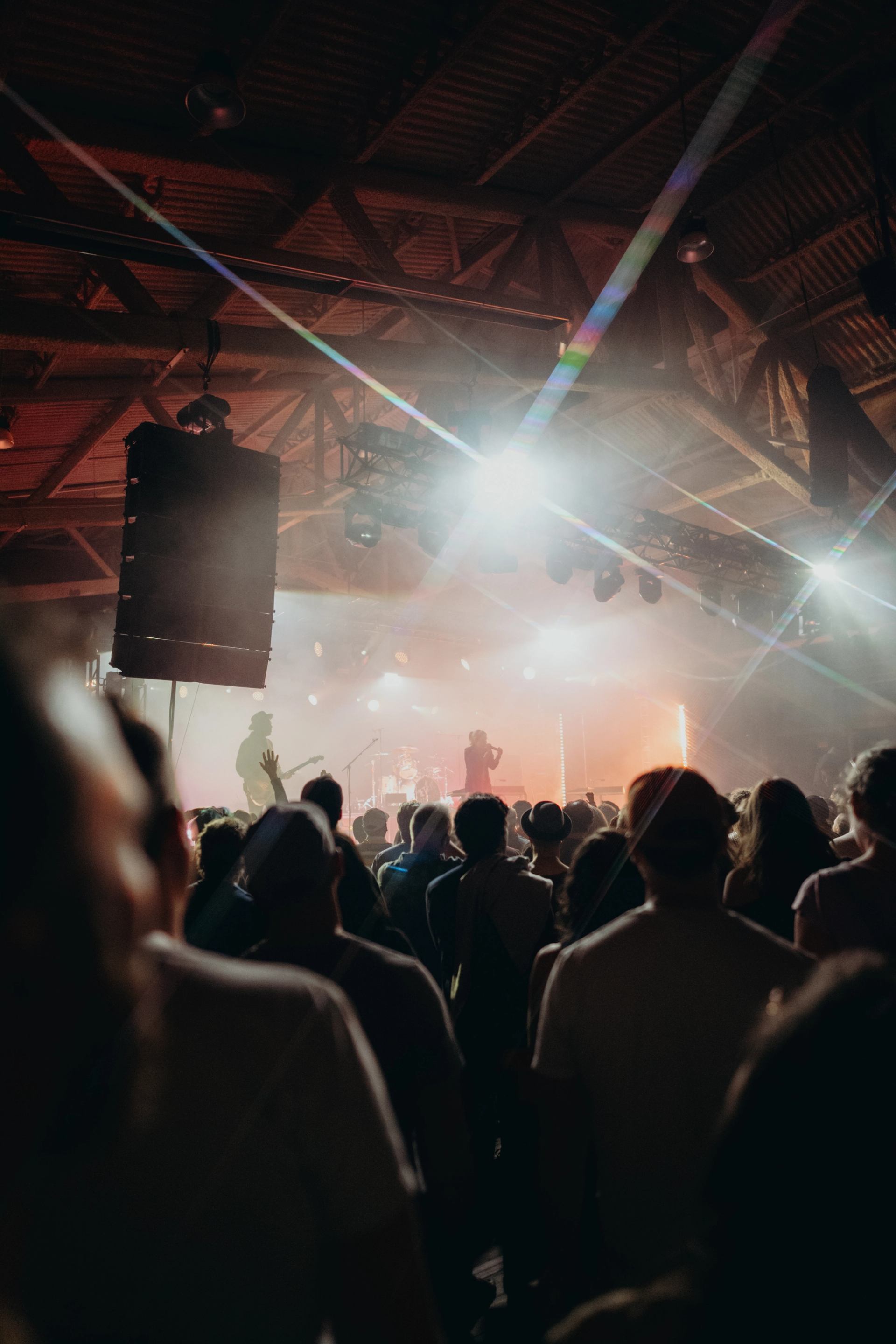 Audience facing a smoky, light‑filled stage during a live show.