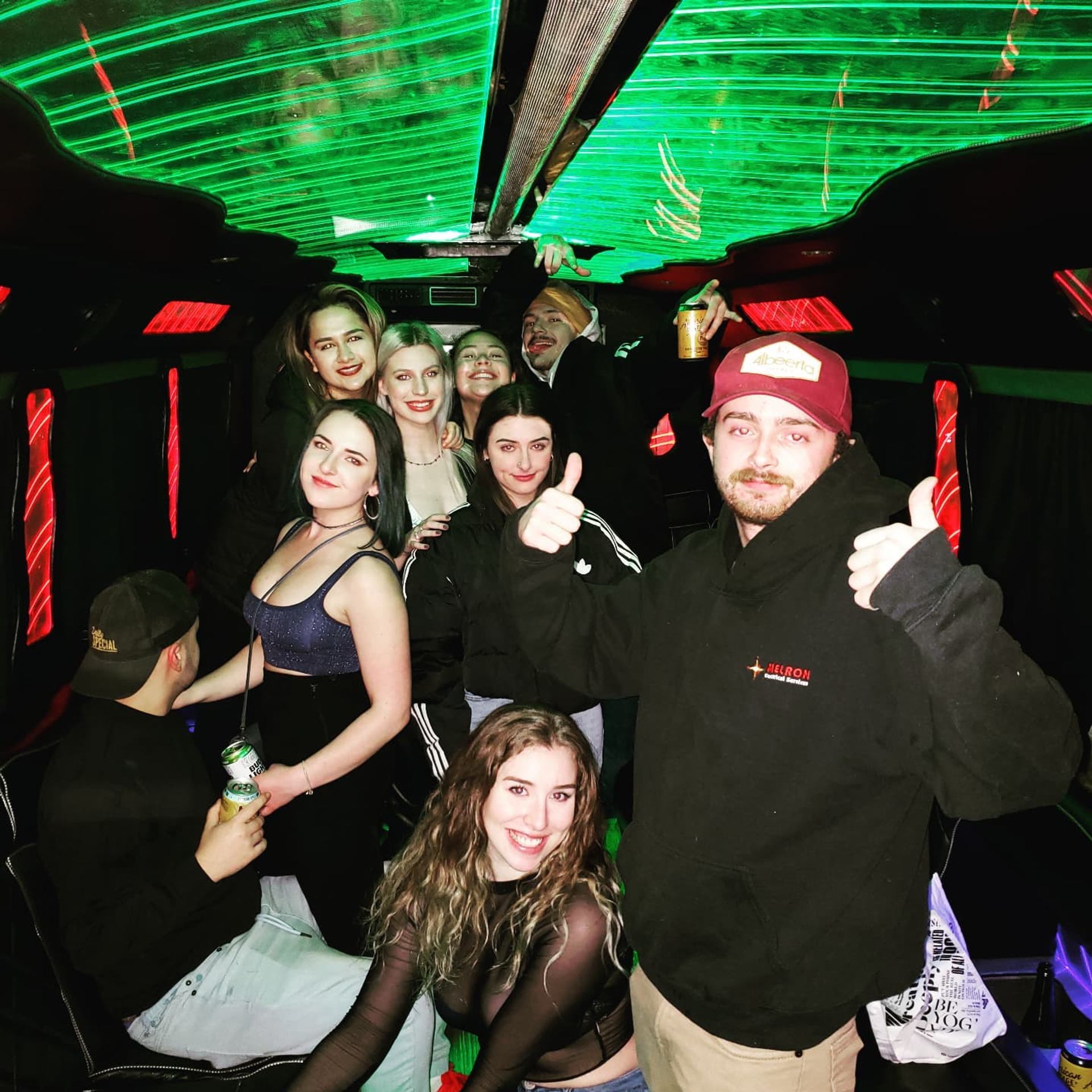 Group celebrating in a party bus with green and red lights, one giving a thumbs-up.