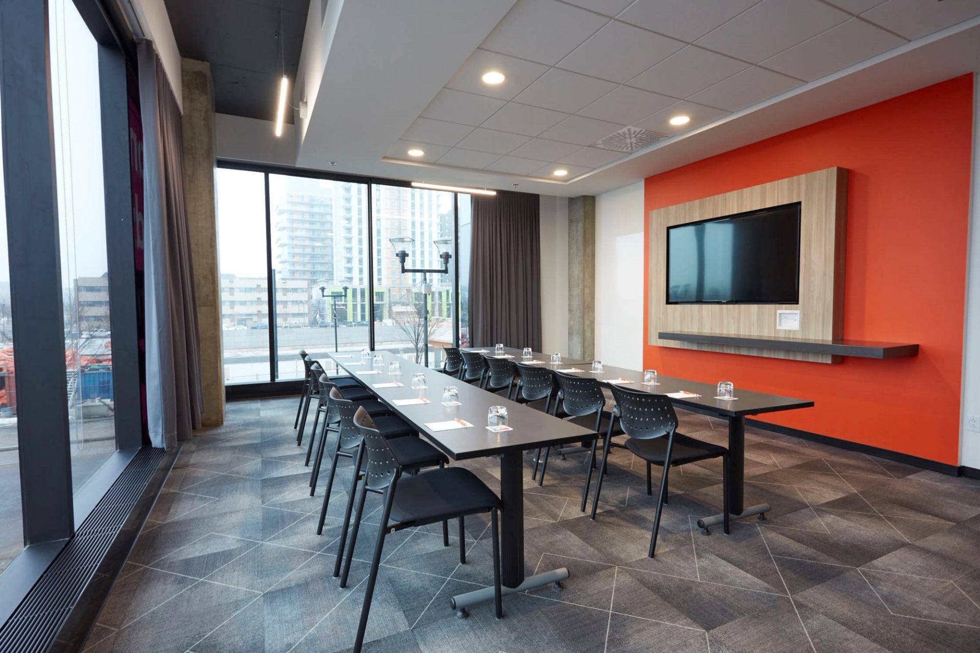 Bright meeting room with long table, chairs, and large windows overlooking the city.