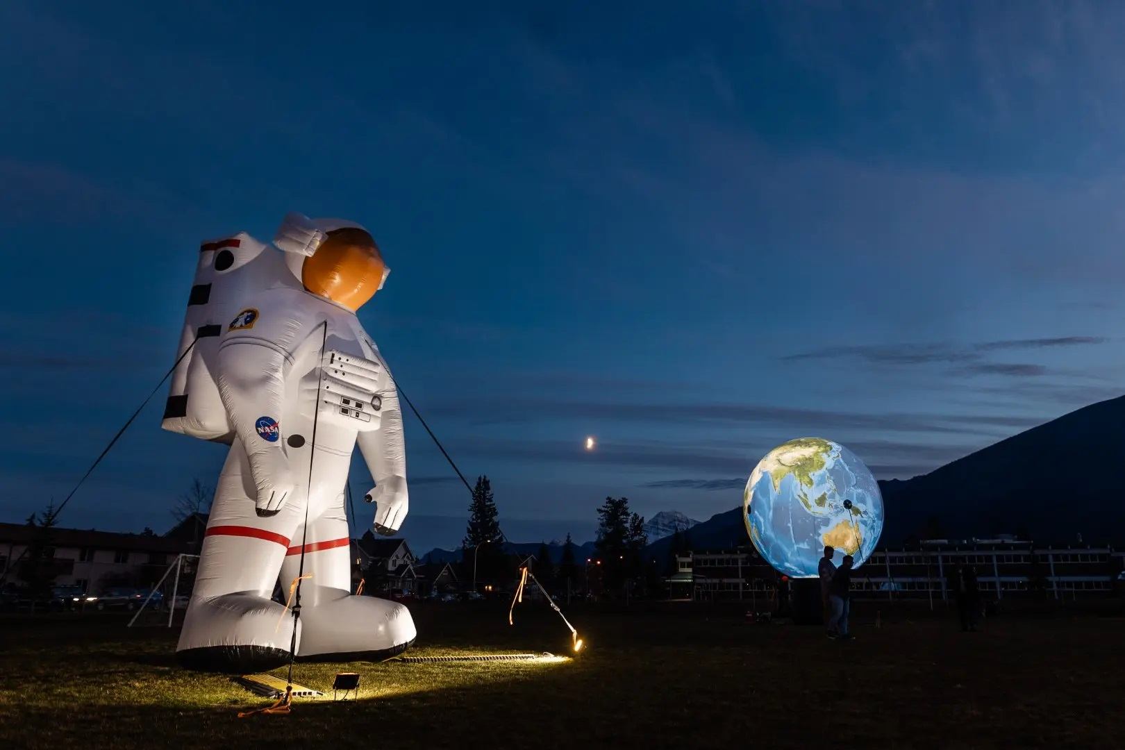 A giant inflatable astronaut and translucent globe are illuminated at night.
