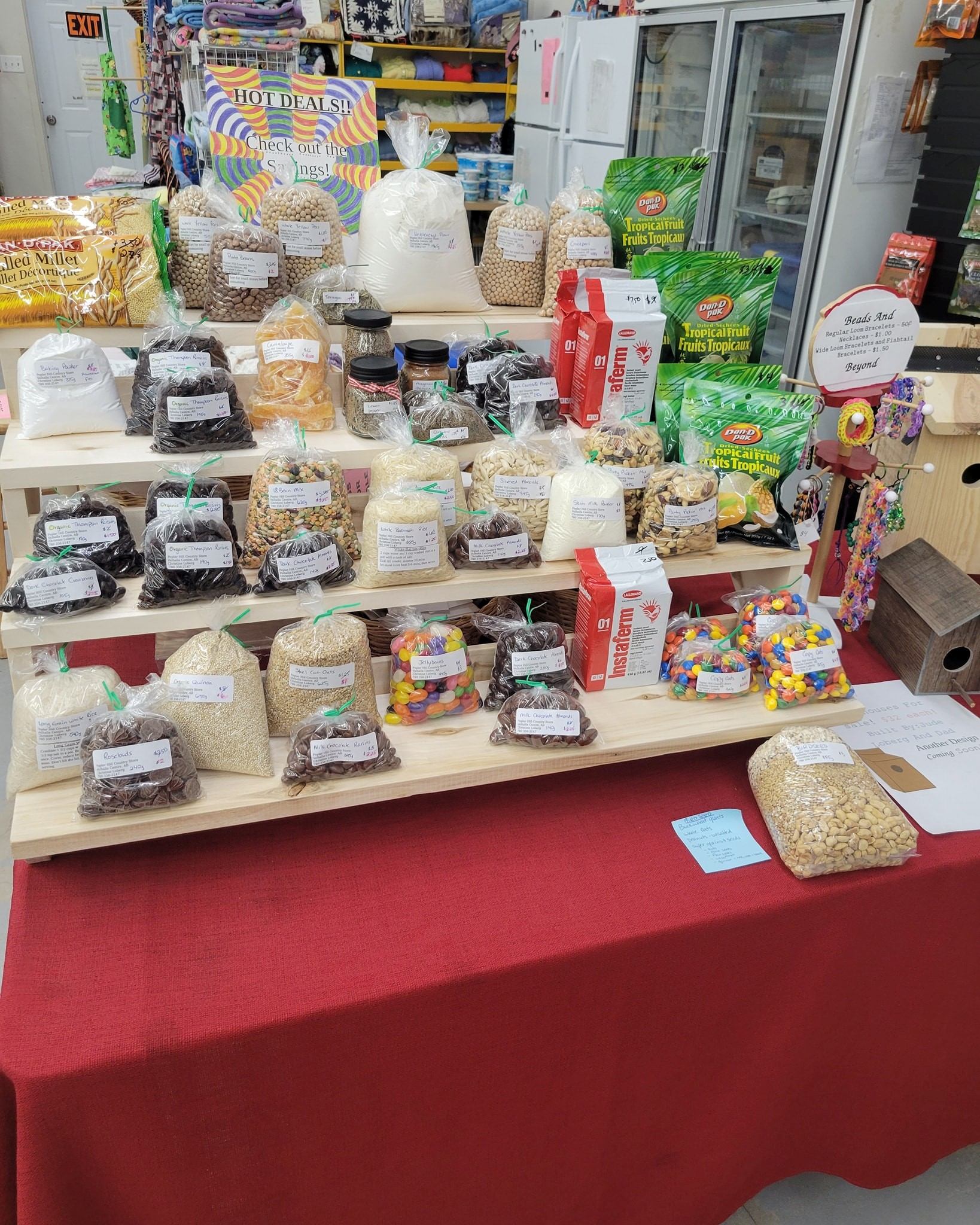 Display of packaged grains, snacks, and pantry items arranged on tiered wooden shelves.