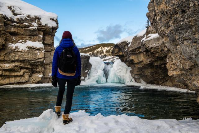 A hiker stops to admire the frozen waterfall at Elbow Falls in Bragg Creek.