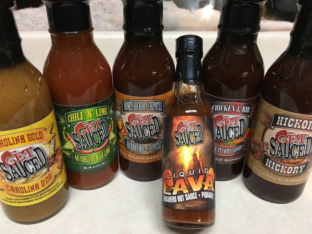 Bottles of Get Sauced barbecue and hot sauces on a counter.