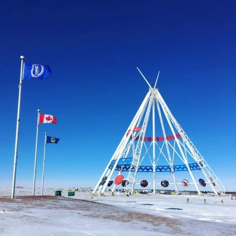 The tipi in the Winter with the local flags flying next to it.